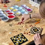 Participantes creando mosaicos con piezas oficiales de LEGO® en un taller de Brickonic , usando piezas de colores organizadas sobre una mesa.